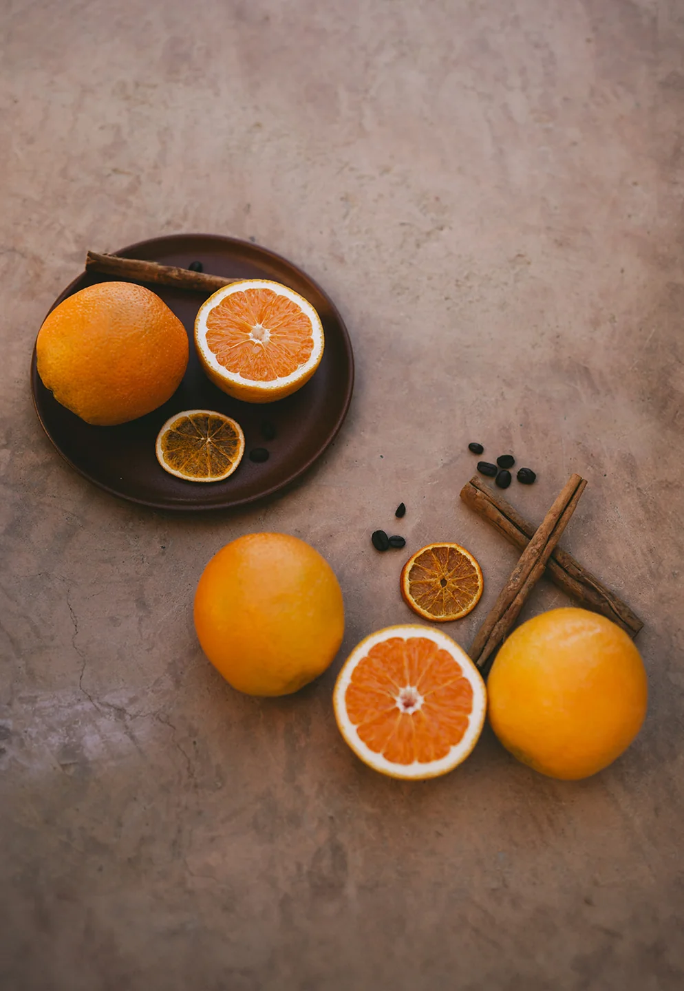 Fresh oranges, dried citrus slices, and cinnamon on a stone table